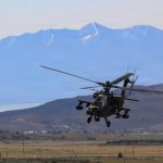 Helicóptero AH-64 Apache del Ejército de EE. UU. en vuelo sobre terreno montañoso.