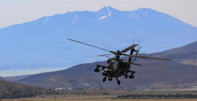 Helicóptero AH-64 Apache del Ejército de EE. UU. en vuelo sobre terreno montañoso.