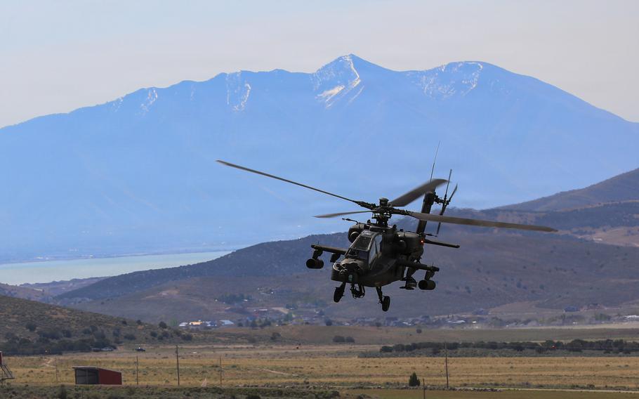 Helicóptero AH-64 Apache del Ejército de EE. UU. en vuelo sobre terreno montañoso.
